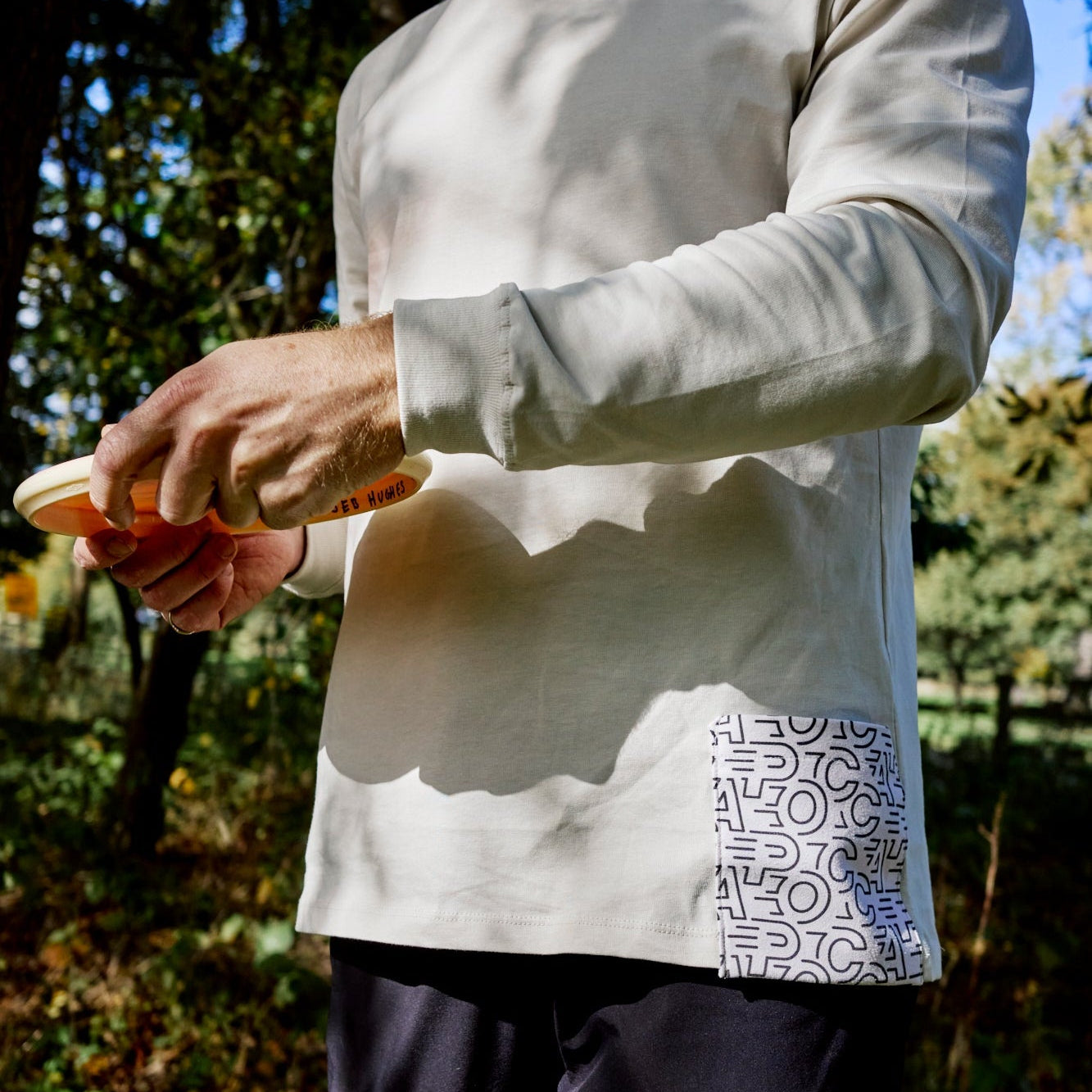 Person wearing a light-colored long-sleeve shirt with geometric patterns with the branding of pocca outdoors.