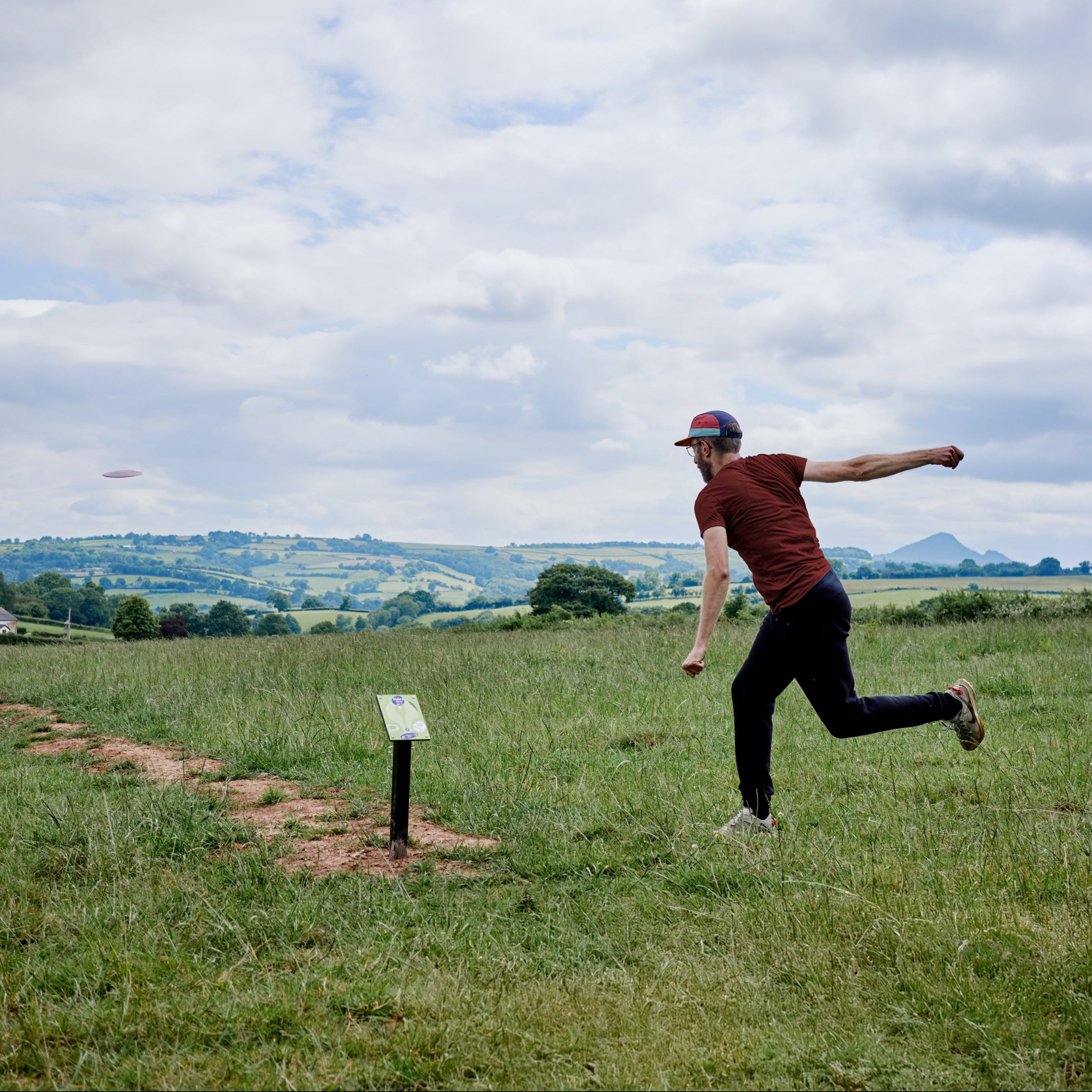 Person playing disc golf in a scenic field with a clear sky
